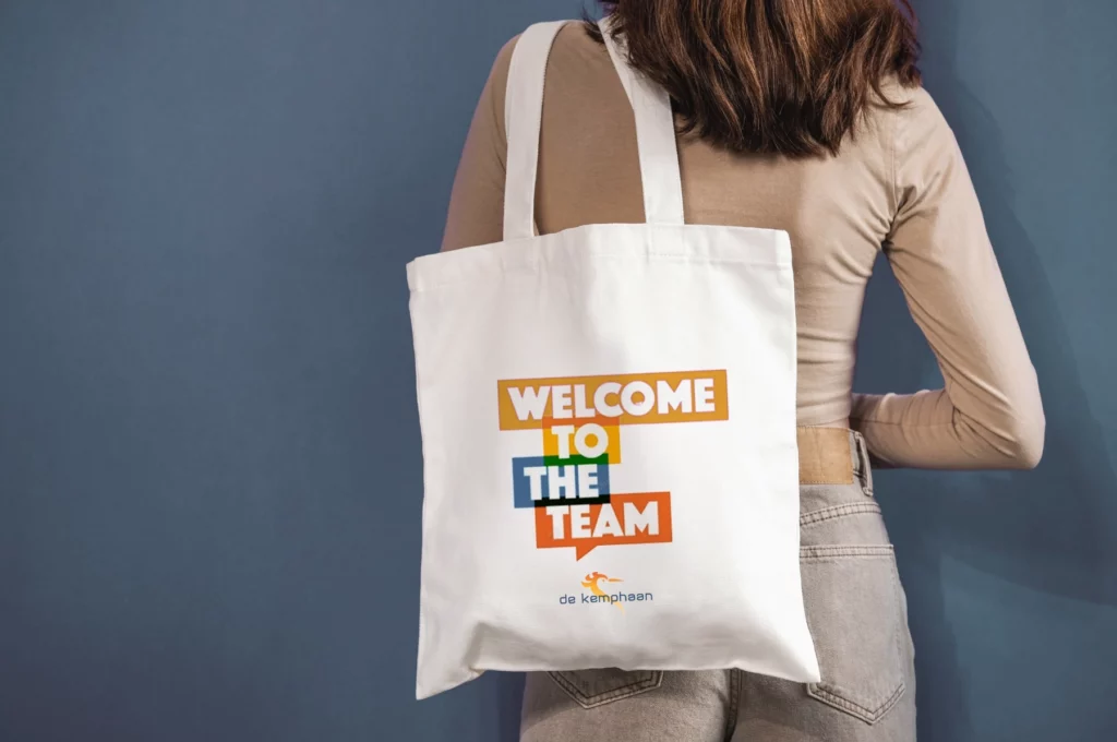 Vrouw met op haar rug een textiel zak met opschrift 'welcome to the team' van De Kemphaan.